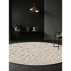 a round rug with an abstract design in beige and grey tones, on a black floor