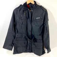 "Belted Waxed Bike Jacket, by Barbour International, in a blue waxed cotton. The jacket has a belt around the waist and four large pockets on the front. It features a Union Jack lining and has a small Union Jack on the back of the collar. The branding is in grey rather than the usual yellow, with Barbour press studs and zips throughout. In good condition, the spoke of neck fastening is missing. Measurements Bust: 38\" Length: 26\" Sleeves : 24\"" Winter Cotton Biker Jacket With Pockets, Casual Biker Jacket With Multiple Pockets For Outdoor, Casual Biker Jacket With Pockets For Outdoor, Cotton Biker Outerwear With Long Sleeve, Cotton Biker Outerwear With Pockets, Bike Jacket, Jack Flag, Union Jack Flag, Barbour International