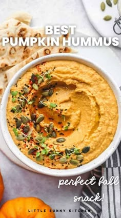 a white bowl filled with hummus next to pumpkins