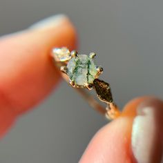 "Handcrafted from a delicate budded twig, the Flora Solitaire Band features a unique Moss Agate  with organic veins threaded throughout the stone in a 6-prong setting. The band is adorned with thyme leaves set with pavé diamonds. 100% recycled gold  100% ethically-sourced Moss Agate Every single ring in my collection is designed, sculpted and produced entirely by hand. I never use computers and I never use \"off-the-shelf\" designs that you see in so many jewelry stores. Each ring begins by cast Nature-inspired Wedding Rings With Natural Stones, Nature-inspired Open Ring Jewelry With Natural Stones, Nature-inspired Jewelry With Natural Stones In Open Ring, Nature-inspired Open Ring With Natural Stones, Nature-inspired Natural Stones Open Ring Jewelry, Nature-inspired Agate Rings With Natural Inclusions, Nature-inspired Natural Stone Open Ring Jewelry, Nature-inspired Moss Agate Jewelry For Anniversary, Nature-inspired Jewelry For Healing With Natural Inclusions