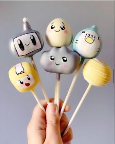 a hand holding several lollipops with faces on them