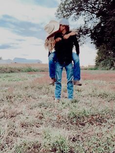 two people are standing in the middle of a field, one is holding the other