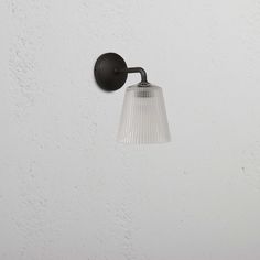 a light that is on the side of a wall with a glass shade hanging from it