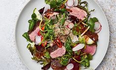 a white plate topped with meat and veggies on top of a marble table