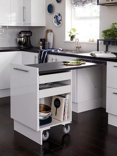 a kitchen with white cabinets and black counter tops is shown in this image, there are plates hanging on the wall