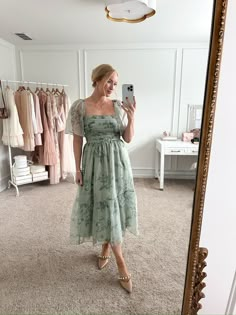 a woman is taking a selfie in front of a mirror wearing a green dress