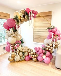 the balloon arch is decorated with pink, gold and white balloons