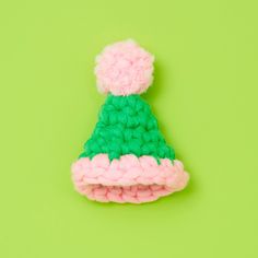 a crocheted hat with pink and green trim on a bright green background in the shape of a pom - pom