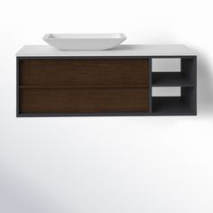 a bathroom sink sitting on top of a wooden cabinet next to a white bowl hanging from the wall