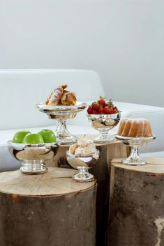 an assortment of desserts sitting on top of wooden stumps in front of a white couch