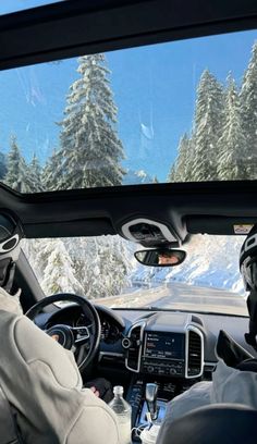 two people in the passenger seat of a car driving down a snow covered mountain road