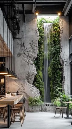 the interior of a restaurant with a waterfall in the wall and tables on either side