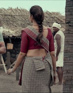 a woman in a sari walking down the street with two men standing behind her