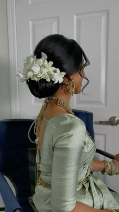 a woman sitting in a chair with flowers in her hair and jewelry on her head