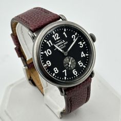 This Shinola watch is a beautiful timepiece that is built to last, and built right here in America.  Features: - Stainless steel case - Shinola red-brown leather strap with no usage  - Tang closure - Includes new Black NATO strap  - Black dial - Gold tone hands - Saphire Crystal - Luminescent hands - A lightning bolt is stamped on the back of each watch, representing Shinola's commitment to quality - Argonite 1069 quartz movement - Water resistant at 50 meters - Built in the US with Swiss and im Classic Red Analog Watch, Classic Red Chronograph Analog Watch, Red Classic Analog Chronograph Watch, Classic Red Analog Chronograph Watch, Formal Brown Watch With Analog Display, Classic Brown Leather Strap Watches, Timeless Brown Watch With Subdials, Red Leather Quartz Watches, Classic Brown Quartz Watch