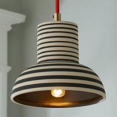 a black and white striped light hanging from a ceiling fixture with a red candle in it