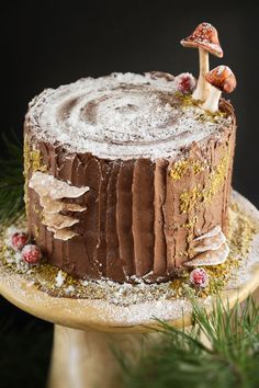 a chocolate cake with frosting and mushrooms on top, sitting on a wooden platter