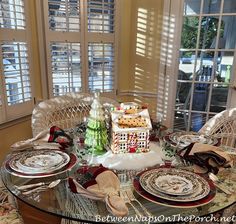 a glass table topped with plates covered in christmas decorations and decorating items on top of it