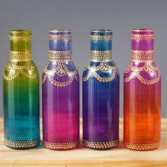 three colorful glass bottles sitting on top of a wooden table