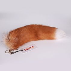 an orange and white fur tail laying on top of a keychain with a tag attached to it