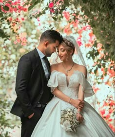 a bride and groom pose for a wedding photo in front of pink flowers on the tree