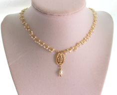 "This is a gold Miraculous Medal Pearl Choker Necklace for women. Absolutely elegant! This necklace is made with 2-3mm fresh water pearls on 24kt gold plated wire, a 14kt gold filled medium size Miraculous medallion 20x13mm at it's center with a Pearl drop. Necklace is adjustable 2\" with a spring clasp in back. Model is wearing a 14\"-16\" length. Comes nicely boxed, the perfect gift! Maybe ordered in 925 Sterling silver." Spiritual Gold Necklaces With Pearl Drop, Spiritual Gold Necklace With Pearl Drop, Gold Spiritual Necklace With Pearl Drop, Gold Pearl Necklace With Spiritual Charm, Spiritual Gold Pearl Necklace With Pearl Charm, Spiritual Gold Pearl Necklace With Charm, Spiritual Gold Pearl Drop Necklace, Gold Pearl Necklace As A Meaningful Gift, Catholic Jewelry Necklace