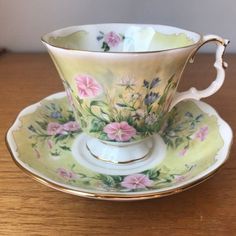 an antique tea cup and saucer on a wooden table with flowers painted on it