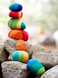 a stack of colorful yarn sitting on top of rocks