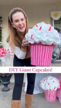 a woman is holding up a giant cupcake