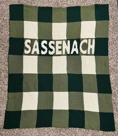 a green and white checkered blanket with the word sasenach written on it