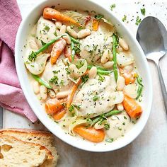 a white bowl filled with chicken and veggies next to a piece of bread