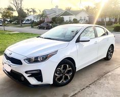 a white car parked on the side of a road in front of a residential area