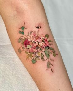 a woman's arm with flowers on it and a bee in the middle tattoo