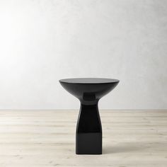 a black table sitting on top of a hard wood floor next to a white wall