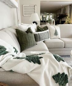 a living room filled with white couches covered in blankets and christmas trees on them