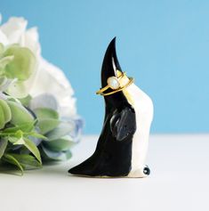 a black and white figurine with a ring on it's head next to flowers