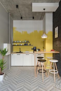 a kitchen with yellow painted walls and stools in front of the counter top area