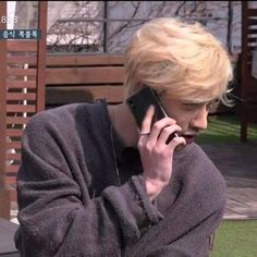 a man talking on a cell phone while sitting in a chair outside with his arm wrapped around him