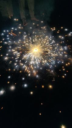 fireworks are lit up in the night sky with people standing around them and looking on