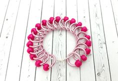 a bracelet with pink beads on a white wooden floor and wood planks in the background