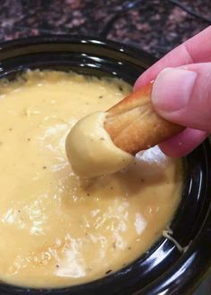 a person dipping cheese into a black bowl