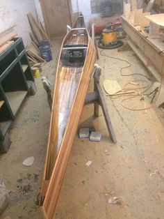 a wooden boat sitting on top of a table in a room filled with woodworking tools