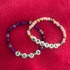 two beaded bracelets with words that spell out the word soul on them sitting on a red surface