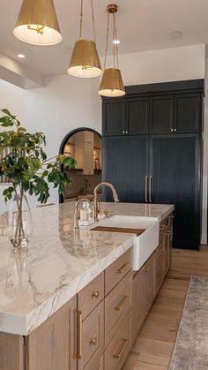 a large kitchen with marble counter tops and gold pendant lights hanging from the ceiling over the sink