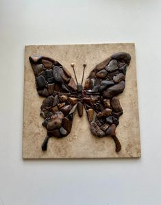 a butterfly made out of rocks sitting on top of a wall