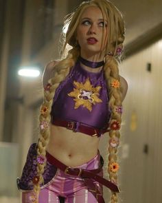 a woman with long blonde hair wearing a purple outfit and braids on her head