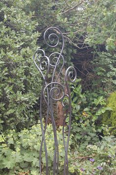 an iron sculpture in the middle of some bushes