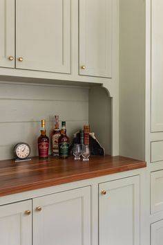 there are many bottles and glasses on the counter top in this kitchen with white cabinets