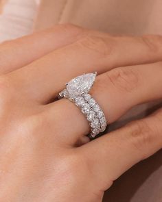 a woman's hand with a diamond ring on top of her finger and an engagement band