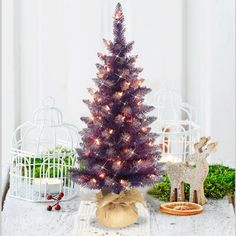 a small purple christmas tree sitting on top of a table next to a deer figurine